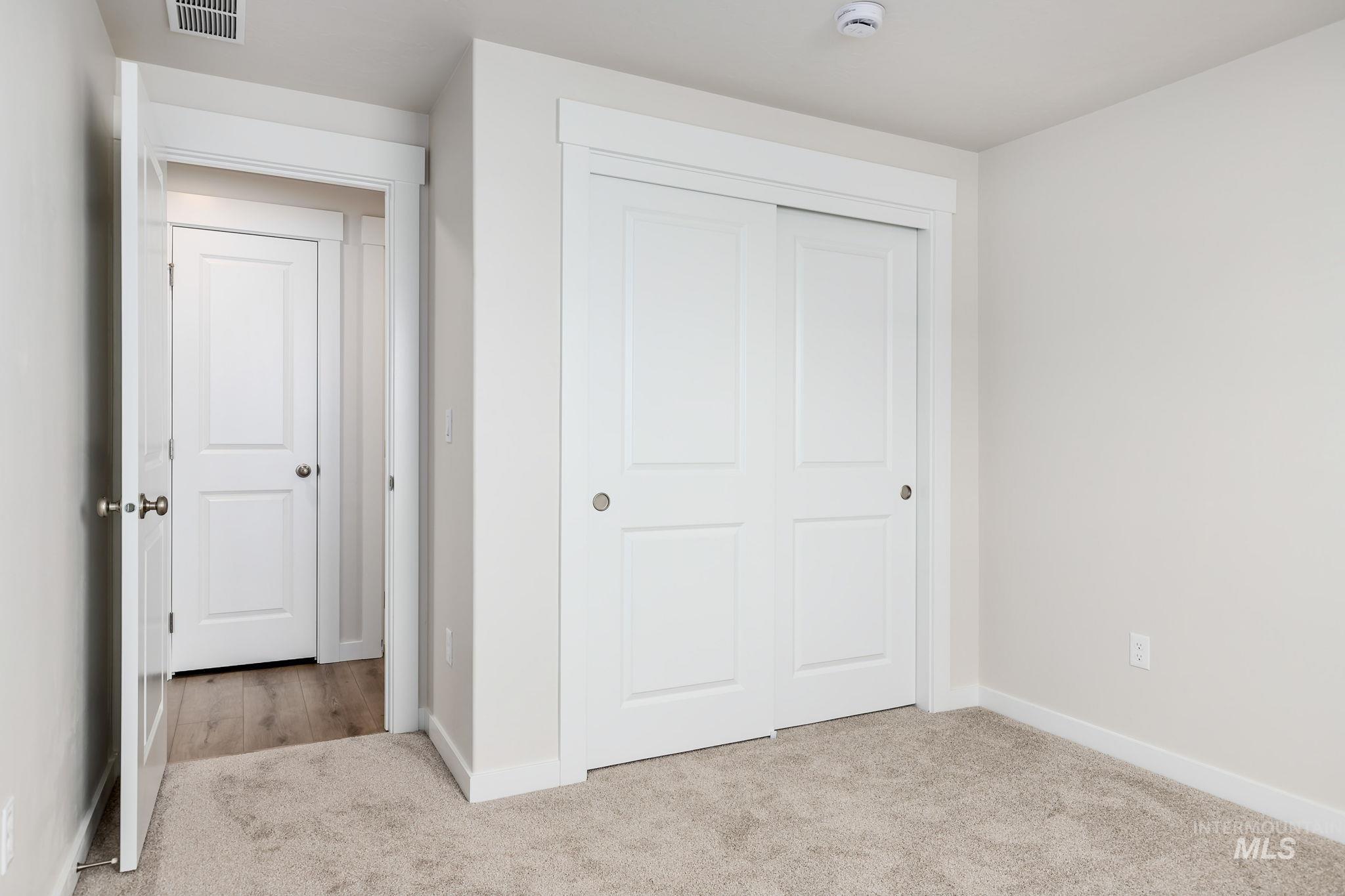 Unfurnished bedroom with light carpet and a closet
