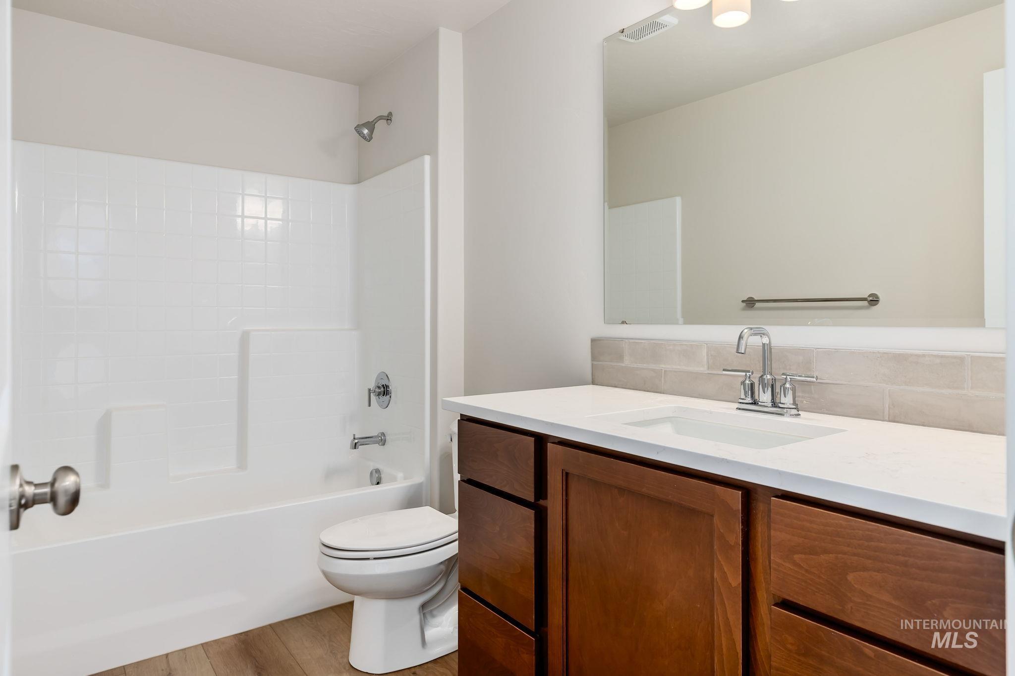 Bathroom featuring vanity, shower / bath combination, and light wood finished floors