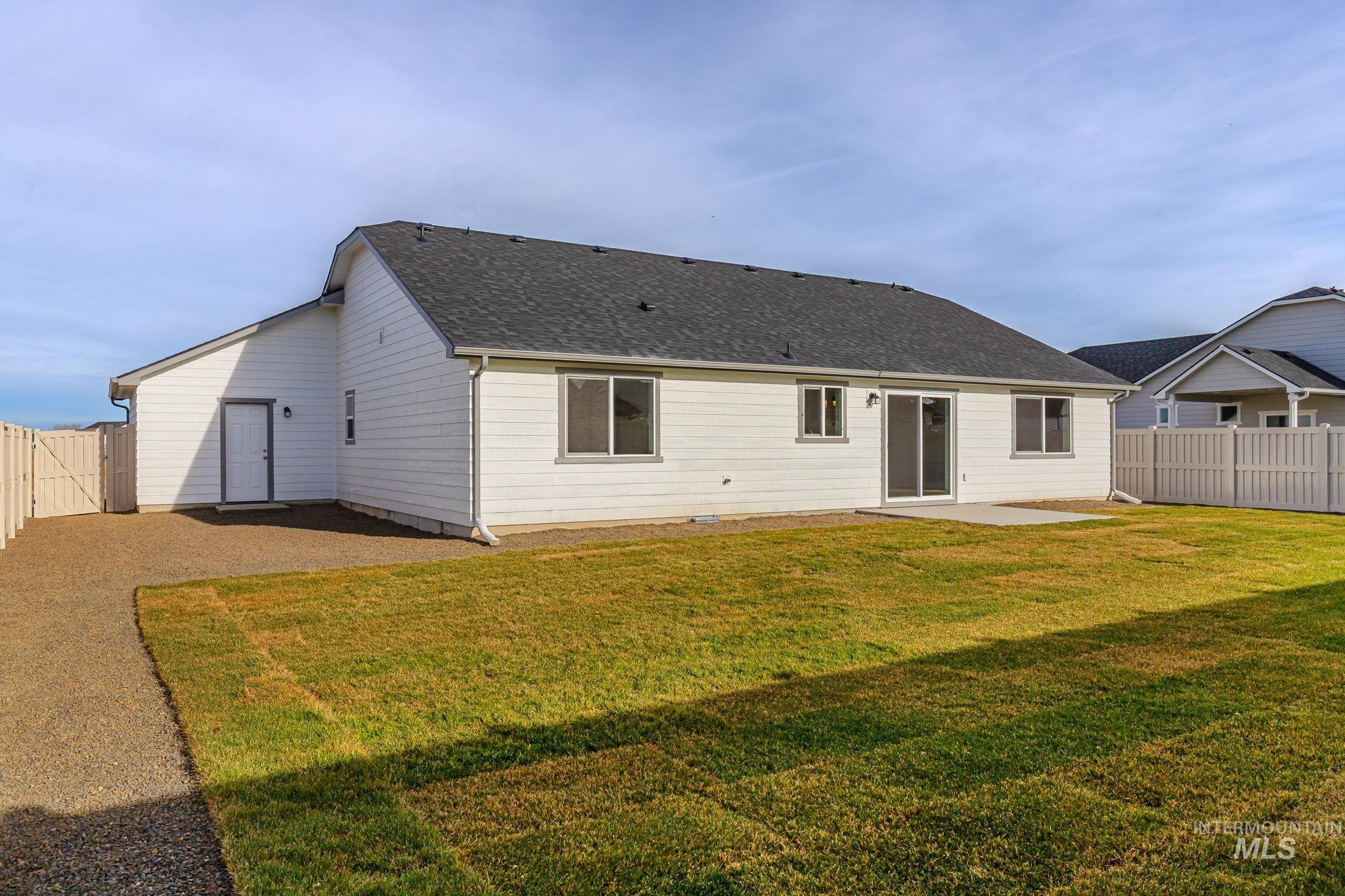 Back of property with a fenced backyard, a patio, and a shingled roof