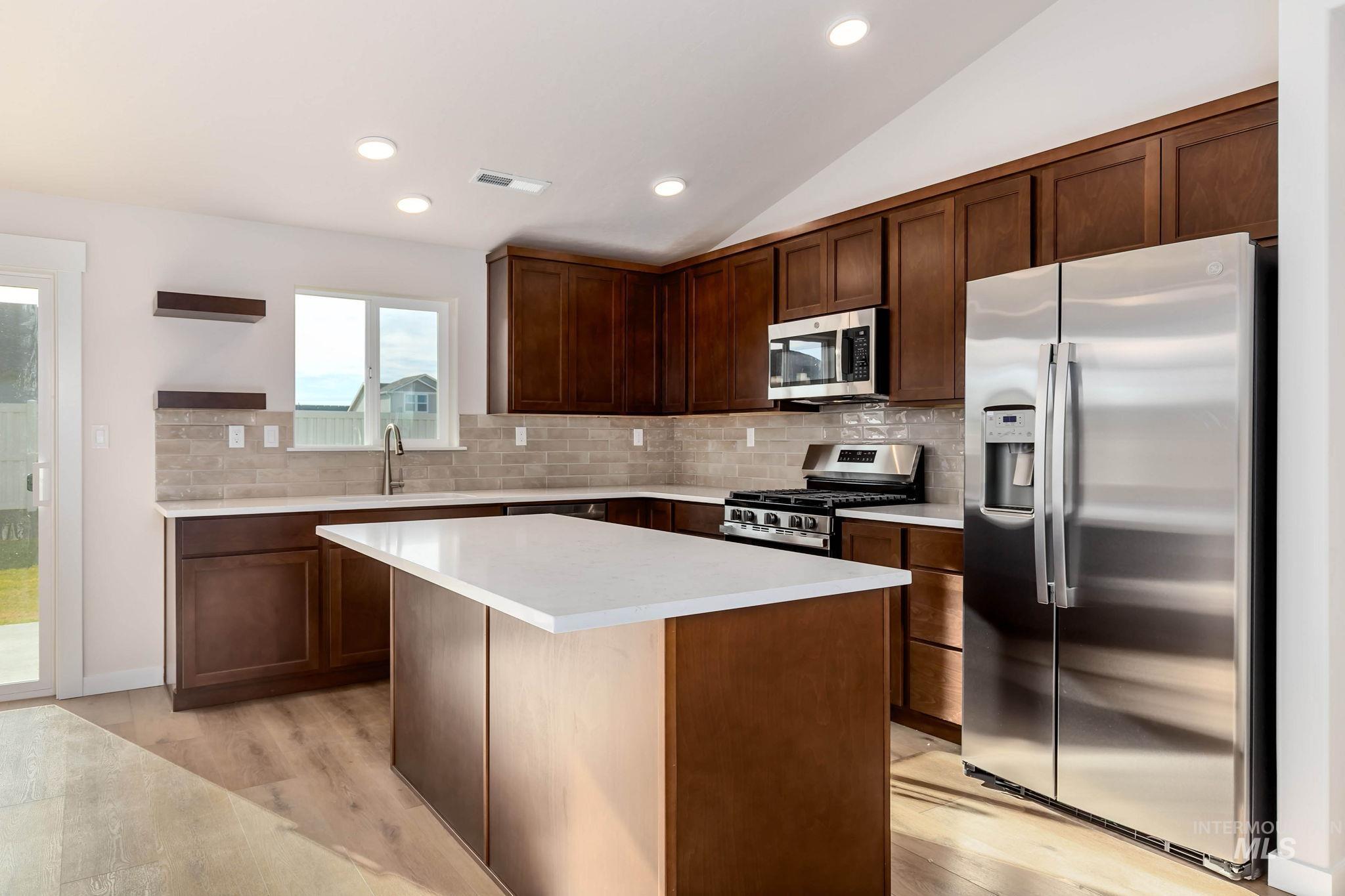 Kitchen with stainless steel appliances, decorative backsplash, a center island, recessed lighting, and open shelves