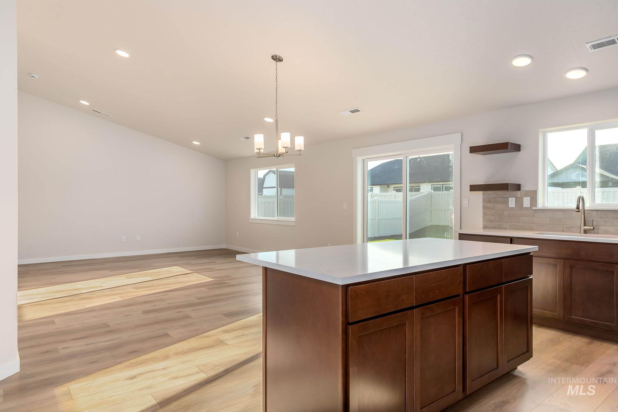 Kitchen with decorative light fixtures, light wood-style floors, open floor plan, recessed lighting, and a center island