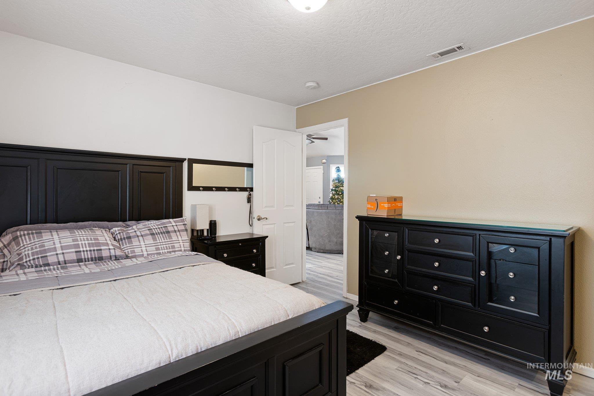 Bedroom with light wood finished floors and a textured ceiling
