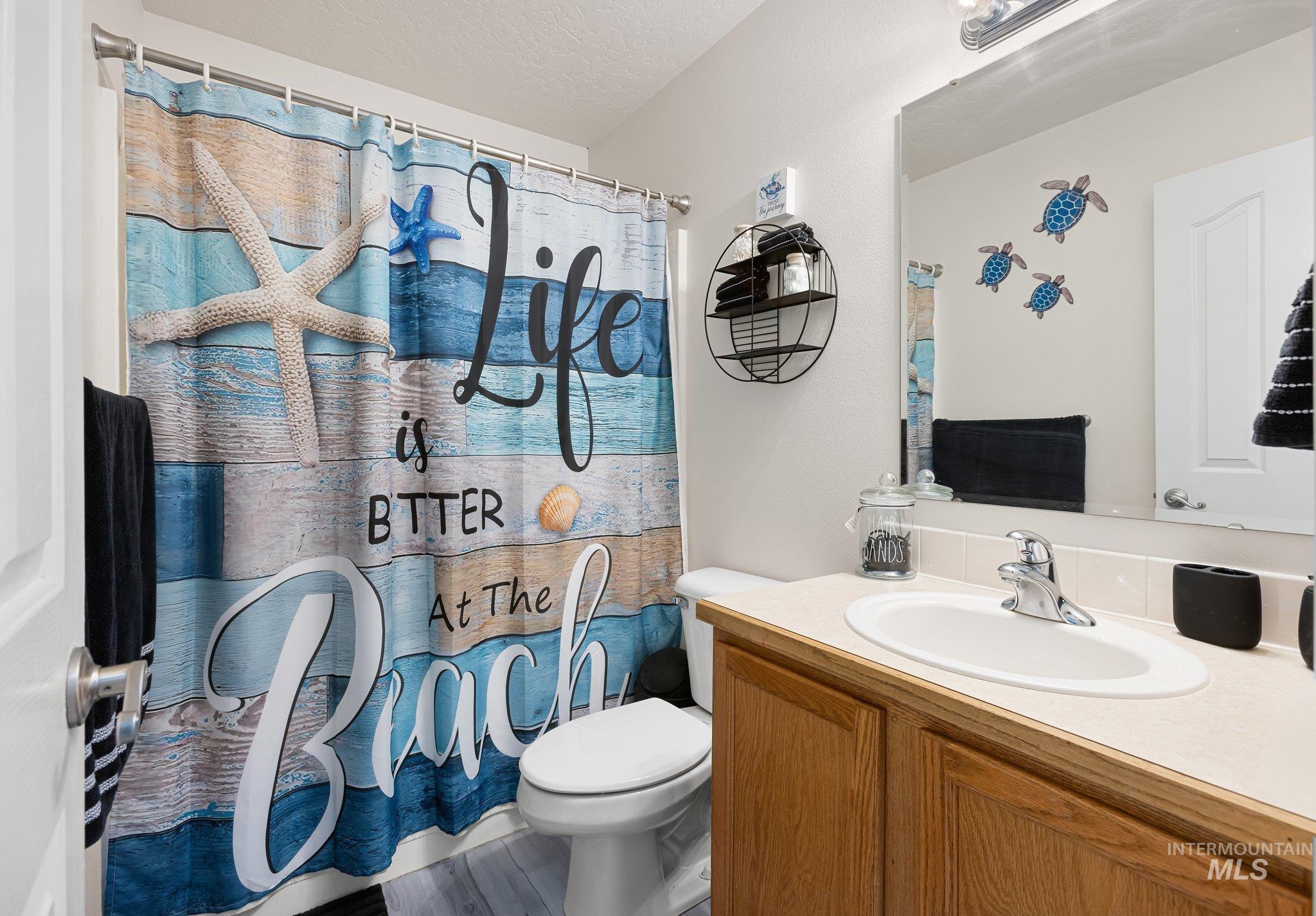 Full bath featuring a shower with curtain, vanity, and a textured ceiling