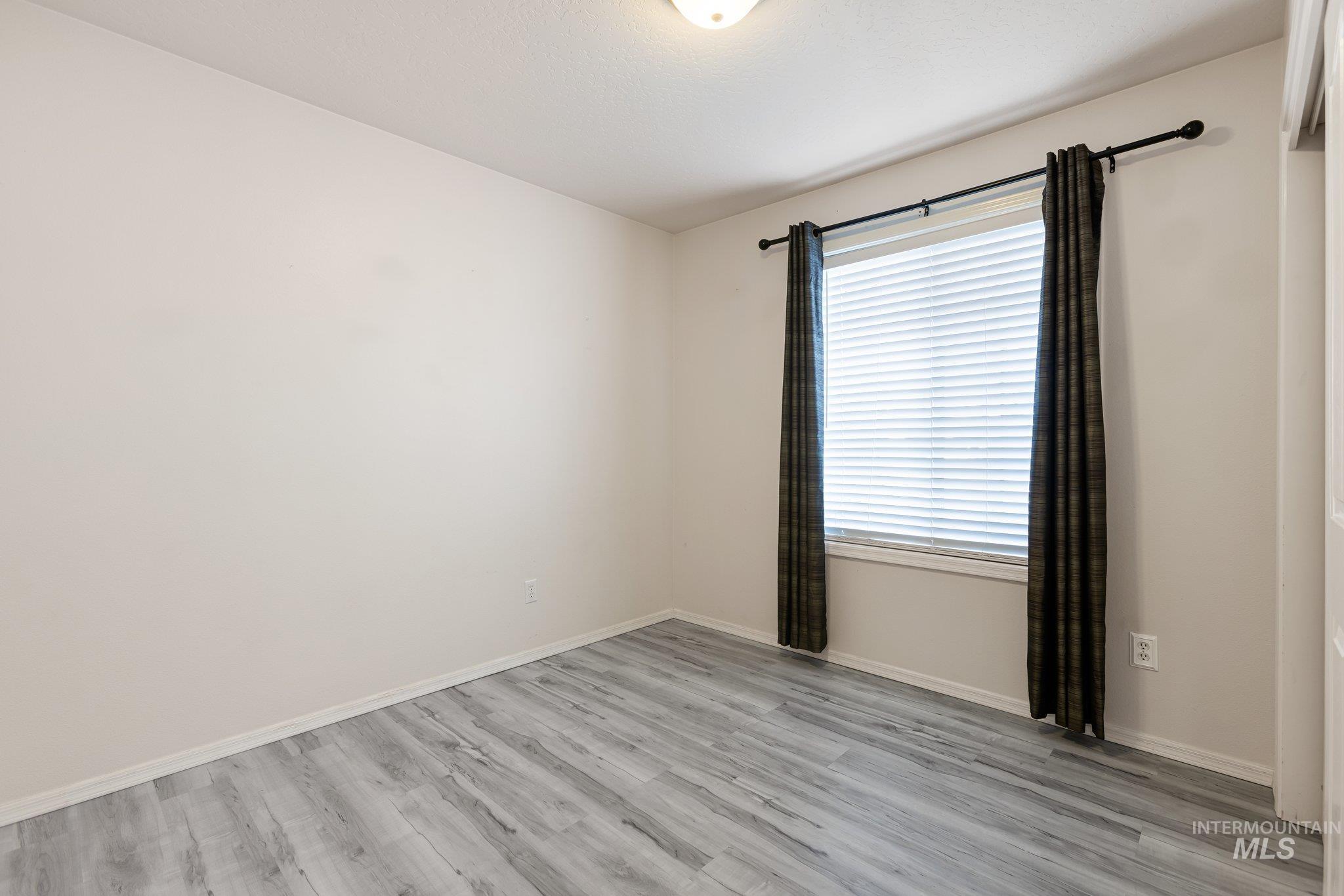 Spare room featuring light wood-style flooring and baseboards