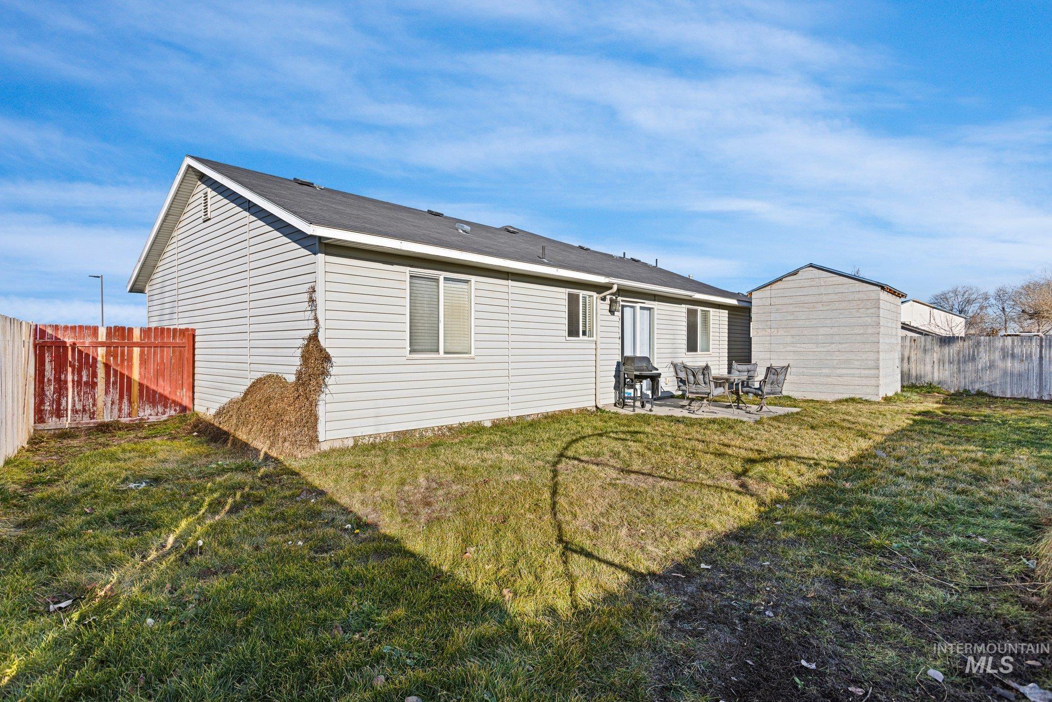 Rear view of house with a fenced backyard and a patio