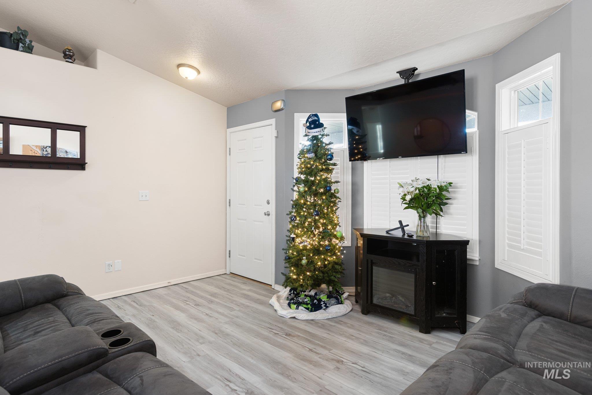Living room with light wood-style flooring, a textured ceiling, and lofted ceiling