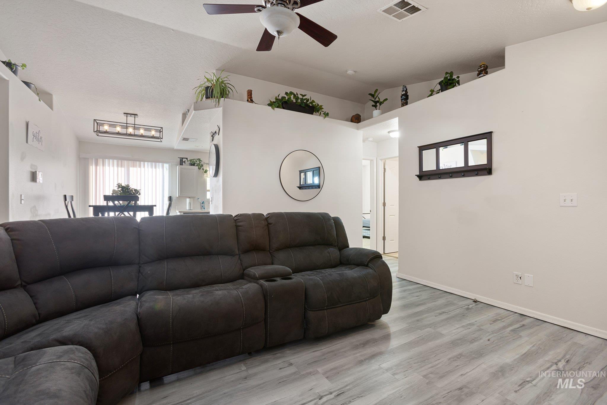 Living room featuring healthy amount of natural light, light wood-style floors, ceiling fan, and vaulted ceiling