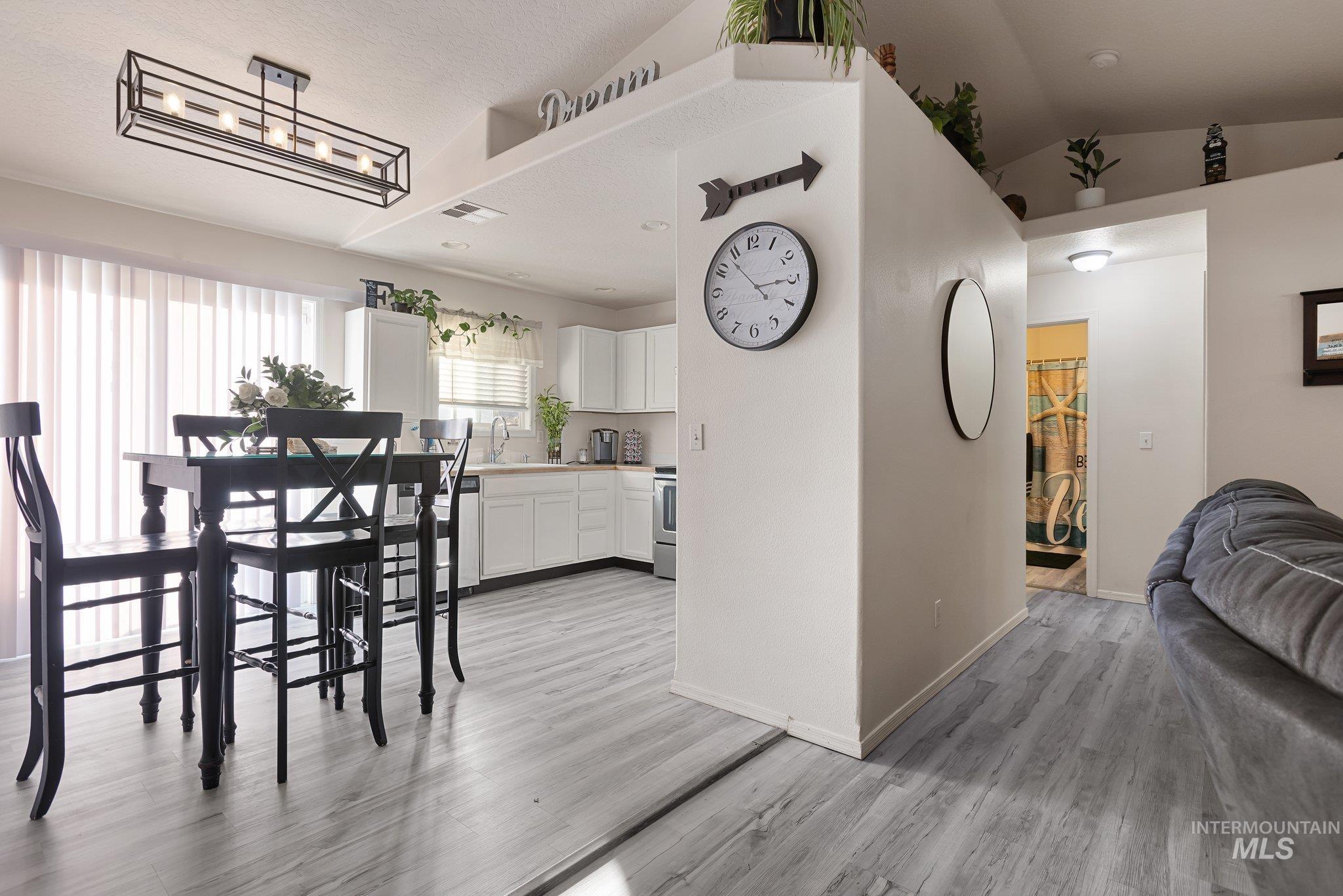 Dining space featuring light wood finished floors and vaulted ceiling