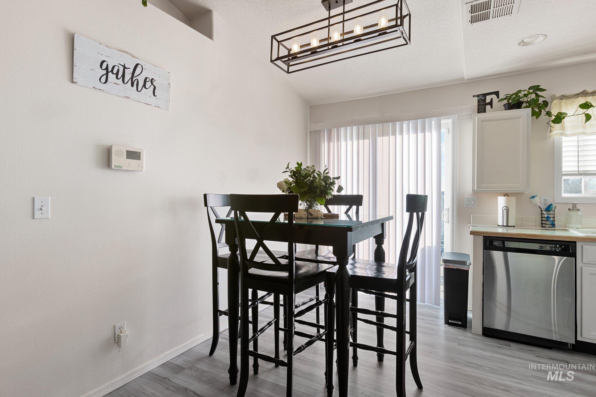 Dining space with plenty of natural light, light wood-style flooring, lofted ceiling, and a textured ceiling