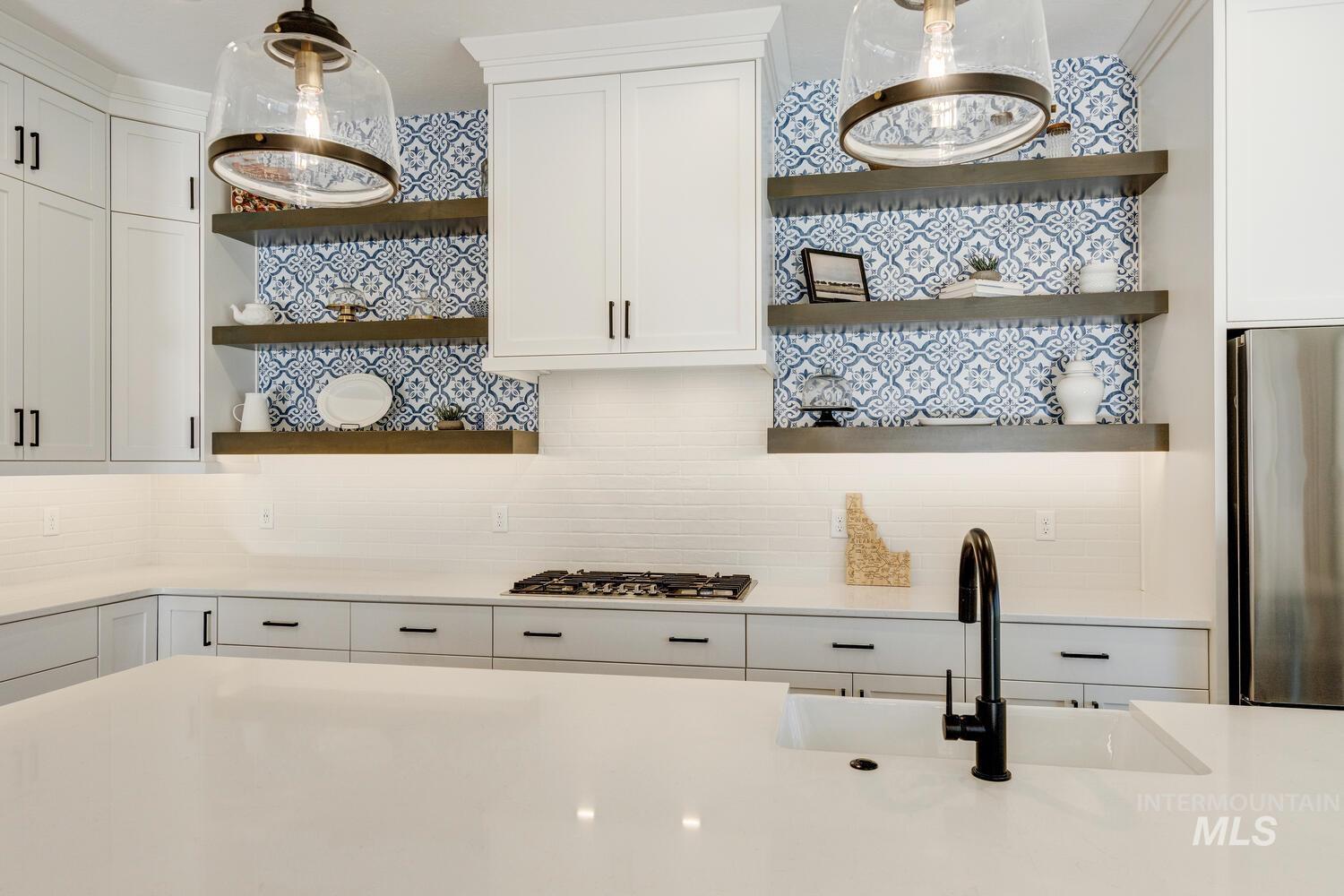 Kitchen with open shelves, white cabinetry, appliances with stainless steel finishes, decorative light fixtures, and tasteful backsplash