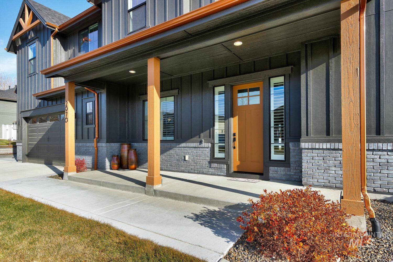 View of exterior entry with a porch, board and batten siding, brick siding, and a garage