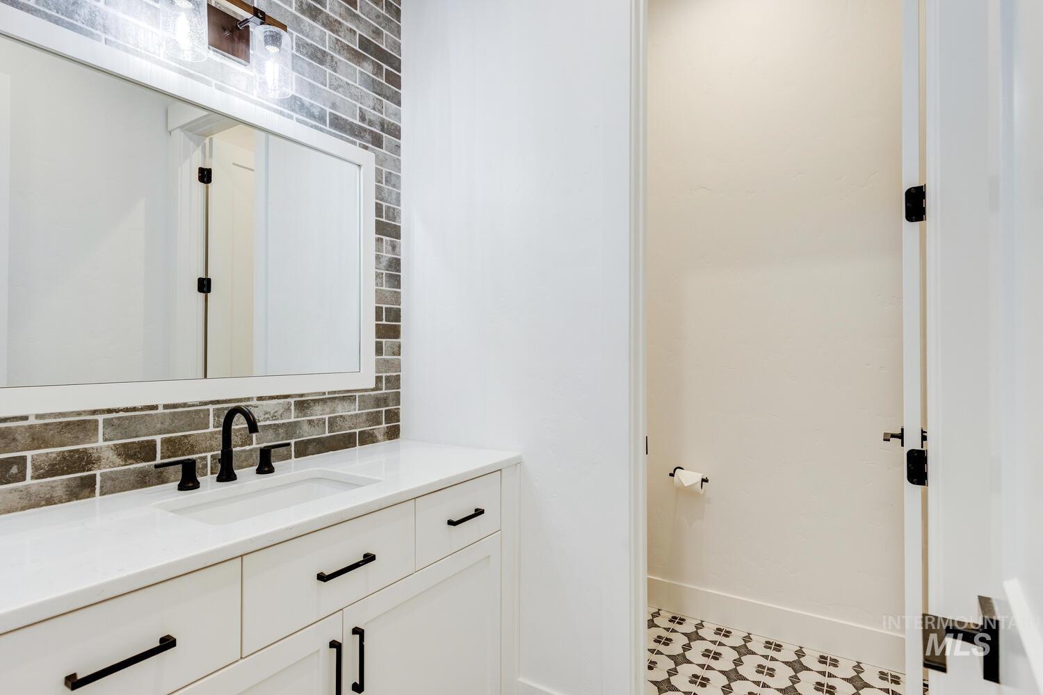 Bathroom with decorative backsplash, vanity, and tile patterned floors