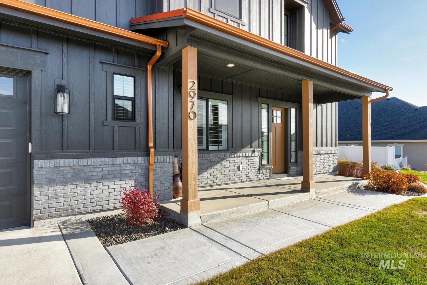 Doorway to property with board and batten siding, a porch, and brick siding