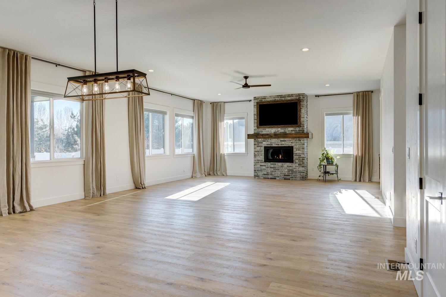 Unfurnished living room with light wood finished floors, a fireplace, ceiling fan, and recessed lighting