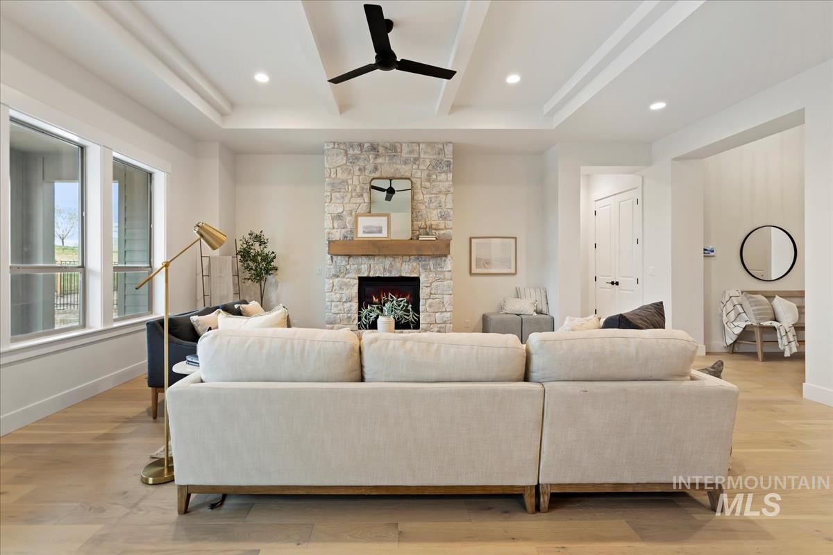 Living area with light wood-style floors, a stone fireplace, ceiling fan, and recessed lighting