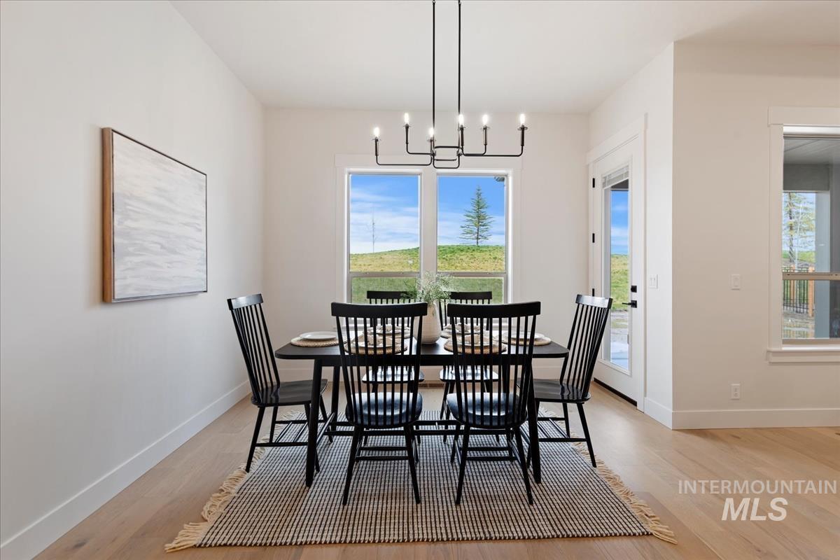Dining room with healthy amount of natural light, light wood-type flooring, and a chandelier