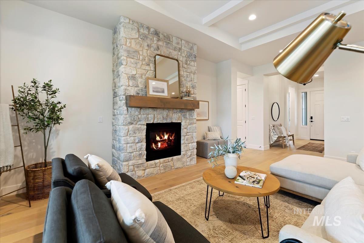 Living area with a fireplace, light wood-style floors, recessed lighting, and beamed ceiling
