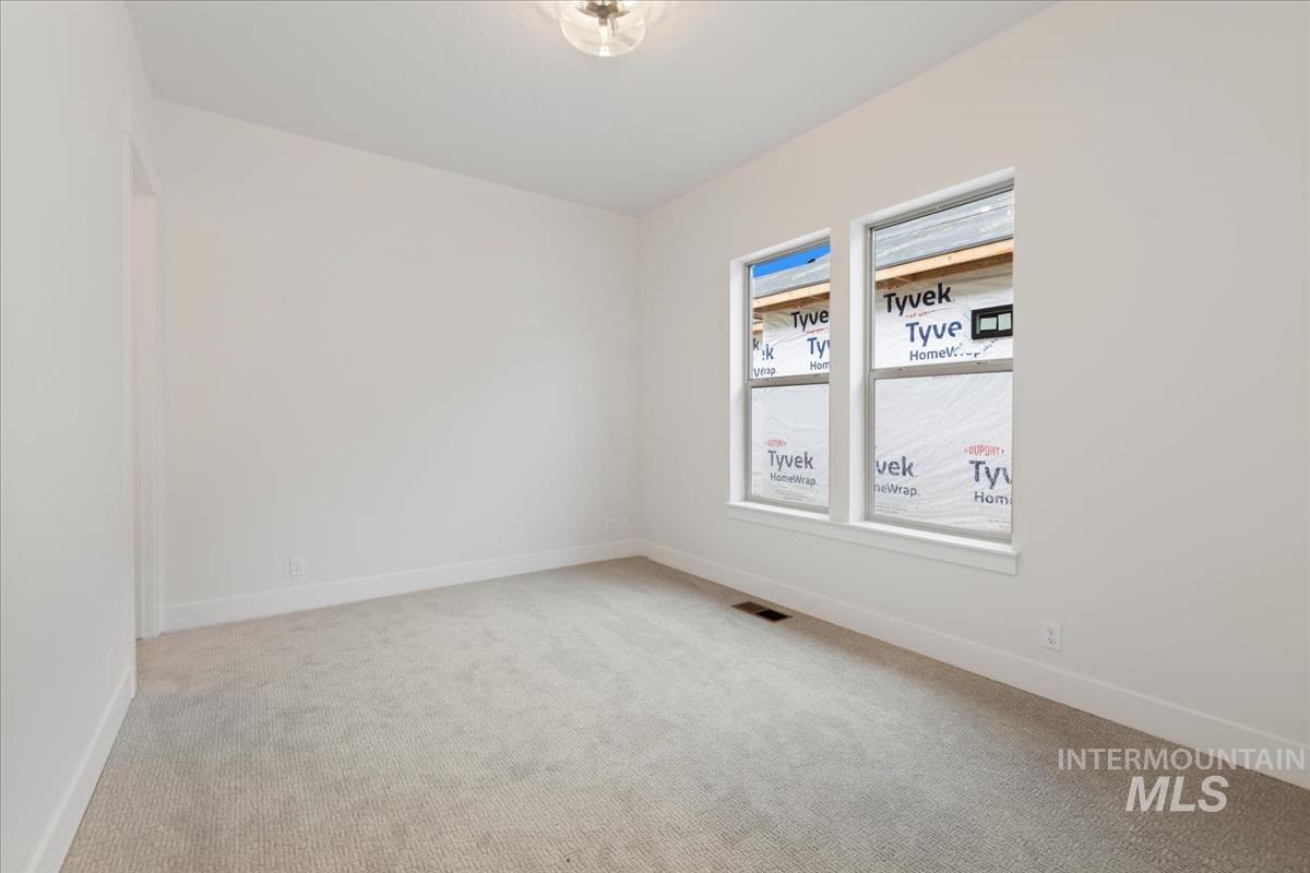 Spare room featuring light carpet and baseboards