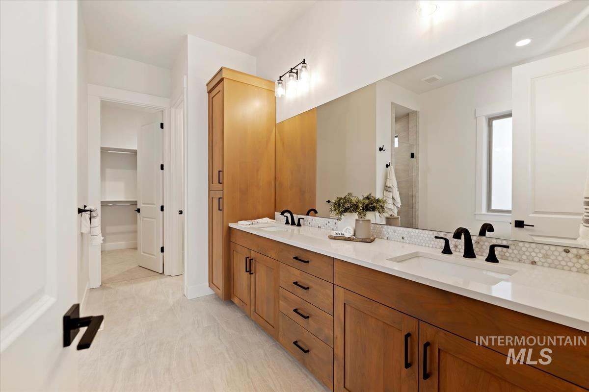 Full bathroom featuring double vanity, a shower stall, and a walk in closet
