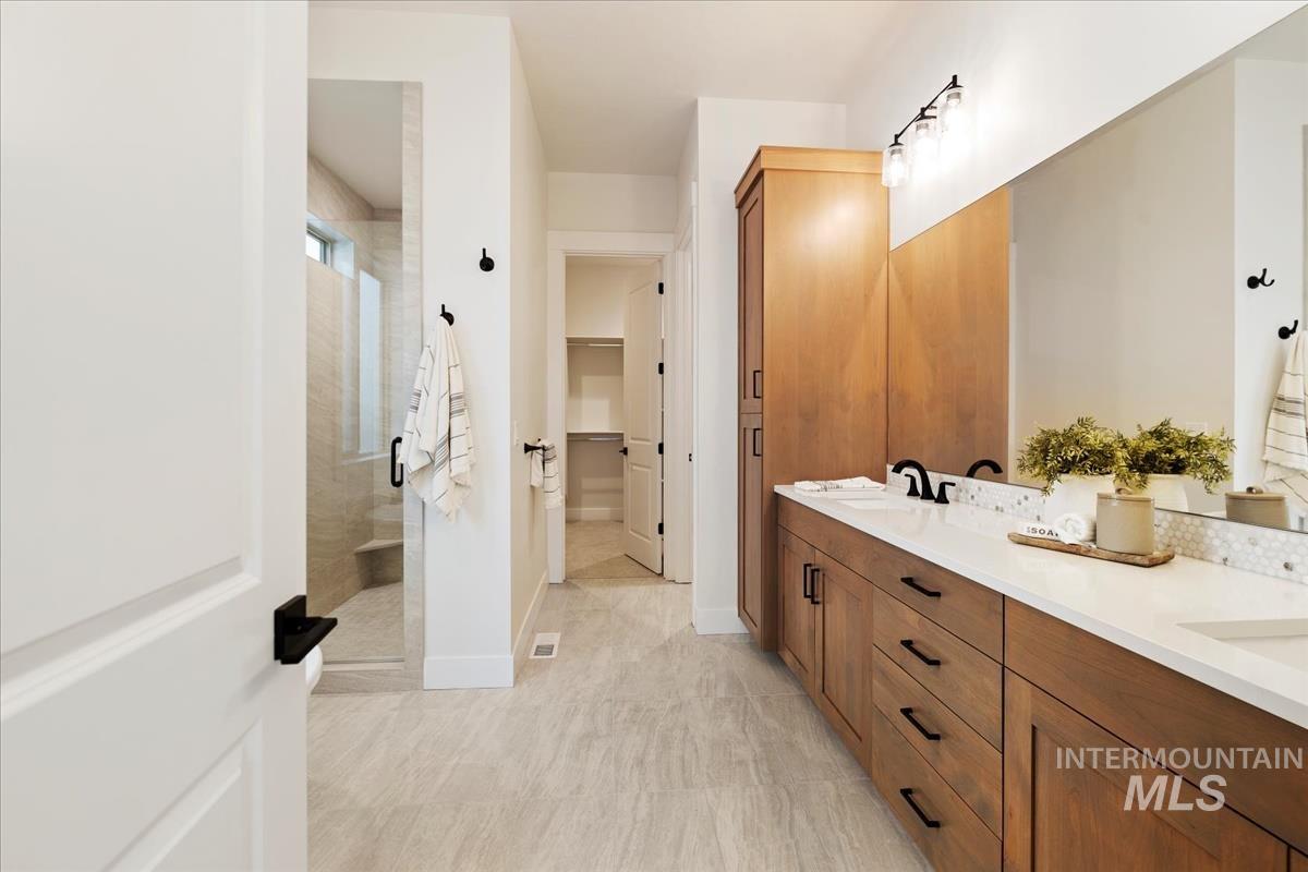 Bathroom featuring double vanity, a stall shower, and a walk in closet