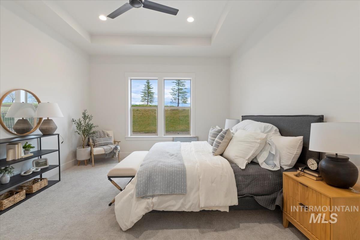 Bedroom featuring light colored carpet, ceiling fan, a tray ceiling, and recessed lighting