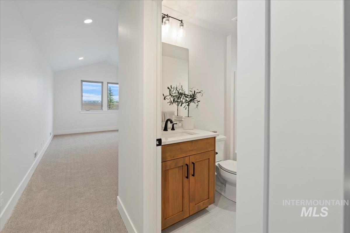Bathroom with vanity, light carpet, lofted ceiling, and recessed lighting