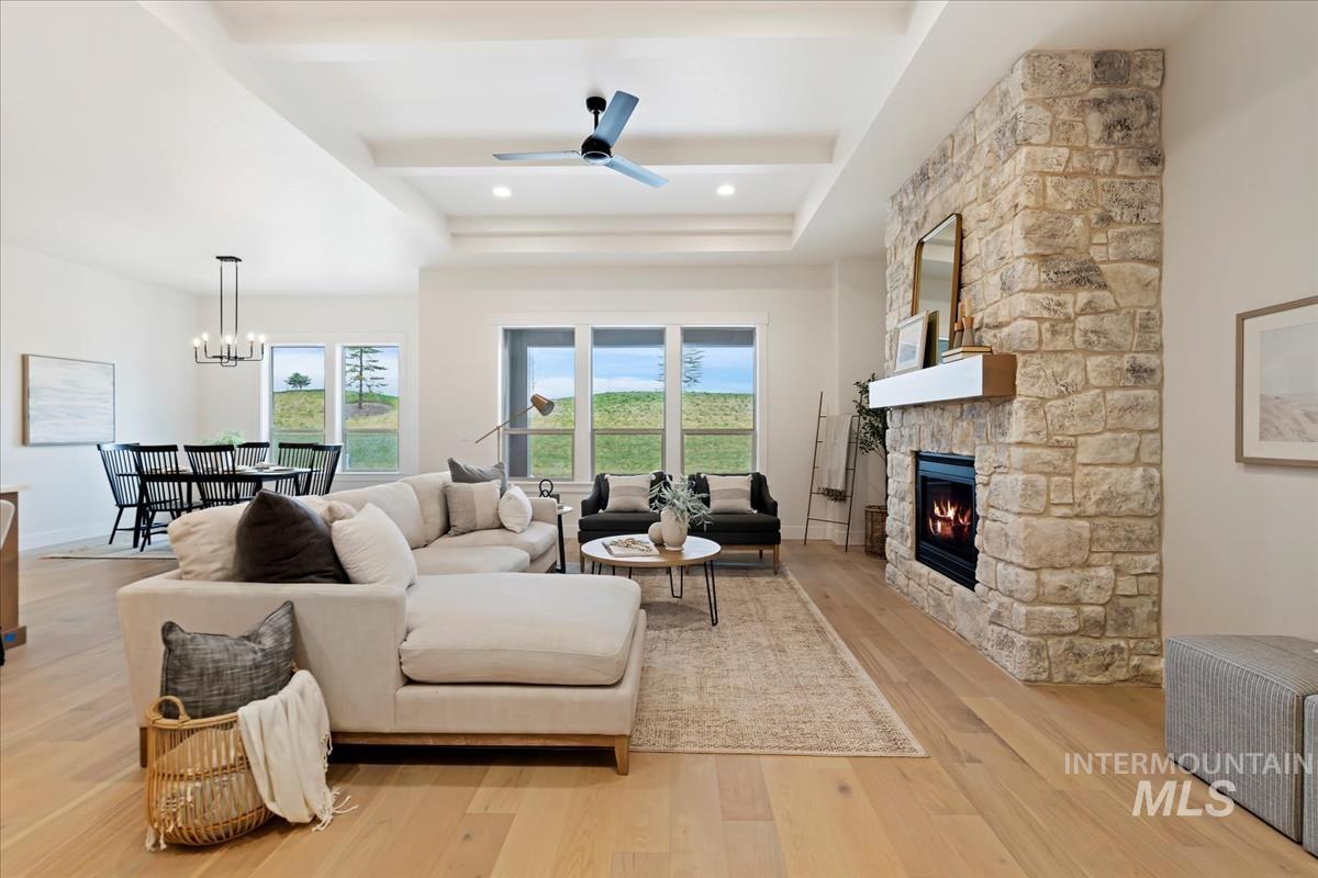 Living room featuring light wood-style flooring, a fireplace, and a ceiling fan