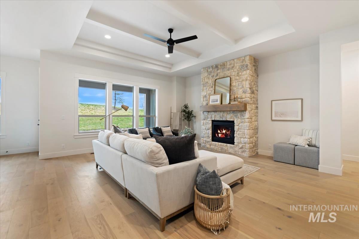 Living room featuring a ceiling fan, a stone fireplace, light wood-type flooring, and recessed lighting
