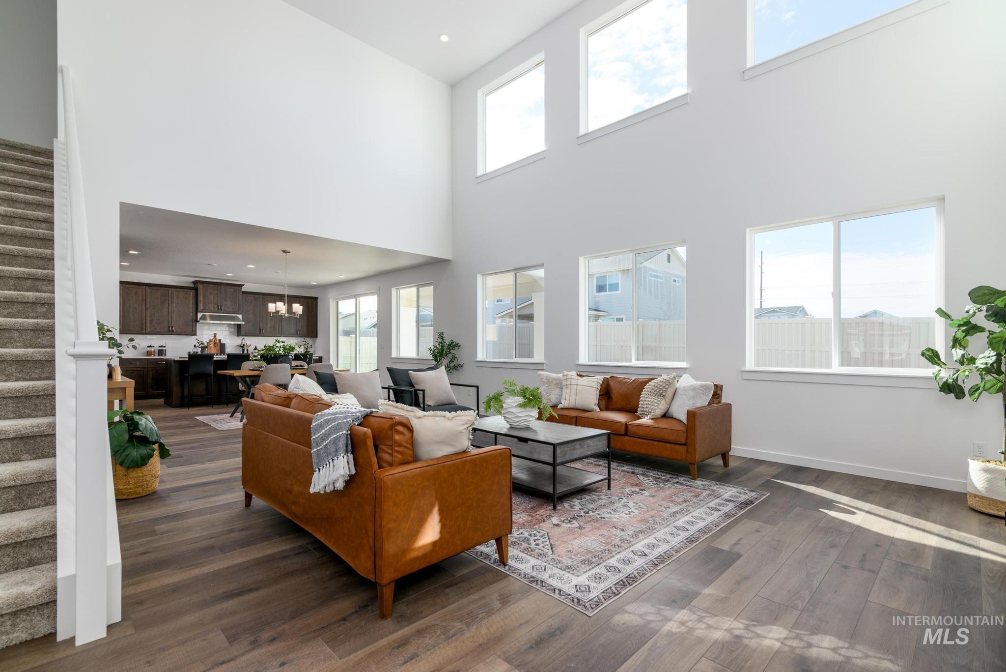 Living room featuring stairs, dark wood finished floors, plenty of natural light, recessed lighting, and a towering ceiling