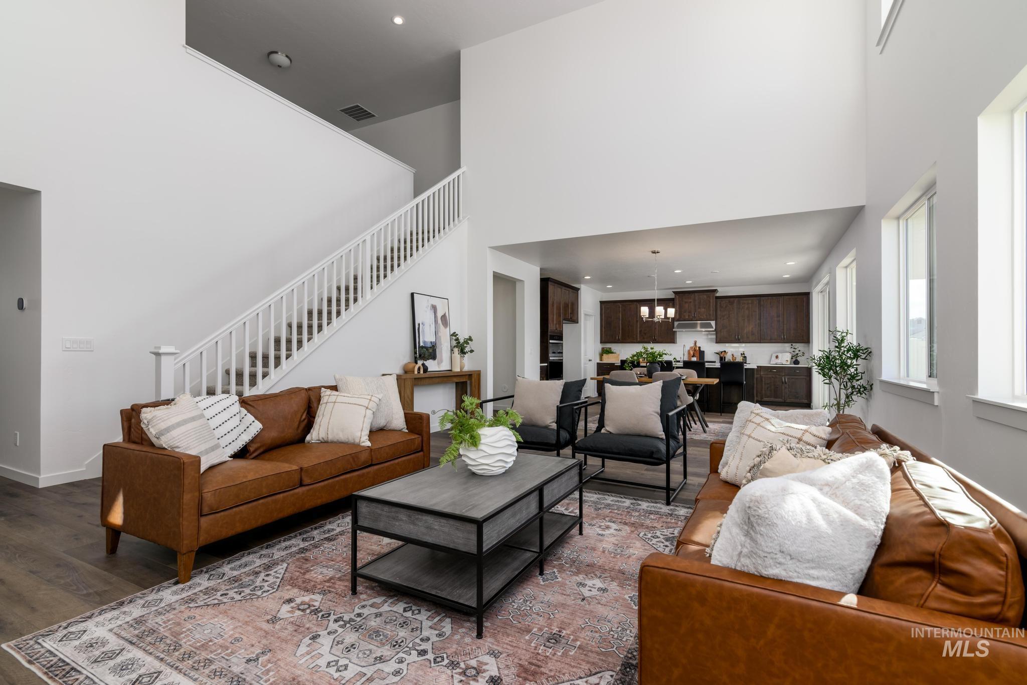 Living area featuring stairs, a chandelier, a towering ceiling, wood finished floors, and recessed lighting