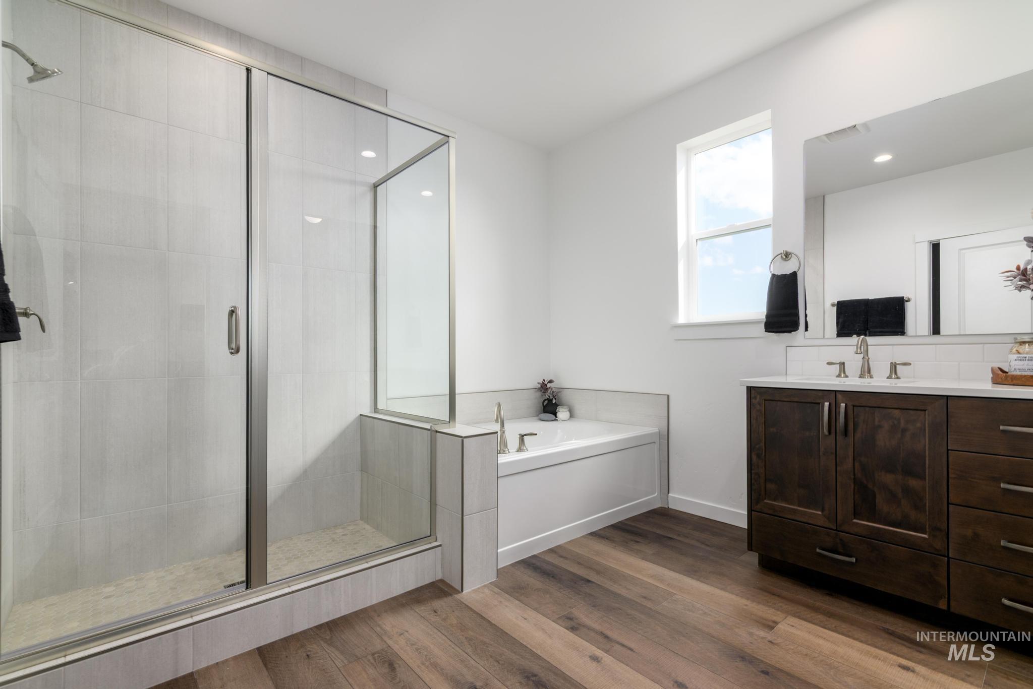 Bathroom with vanity, a garden tub, a stall shower, and dark wood finished floors