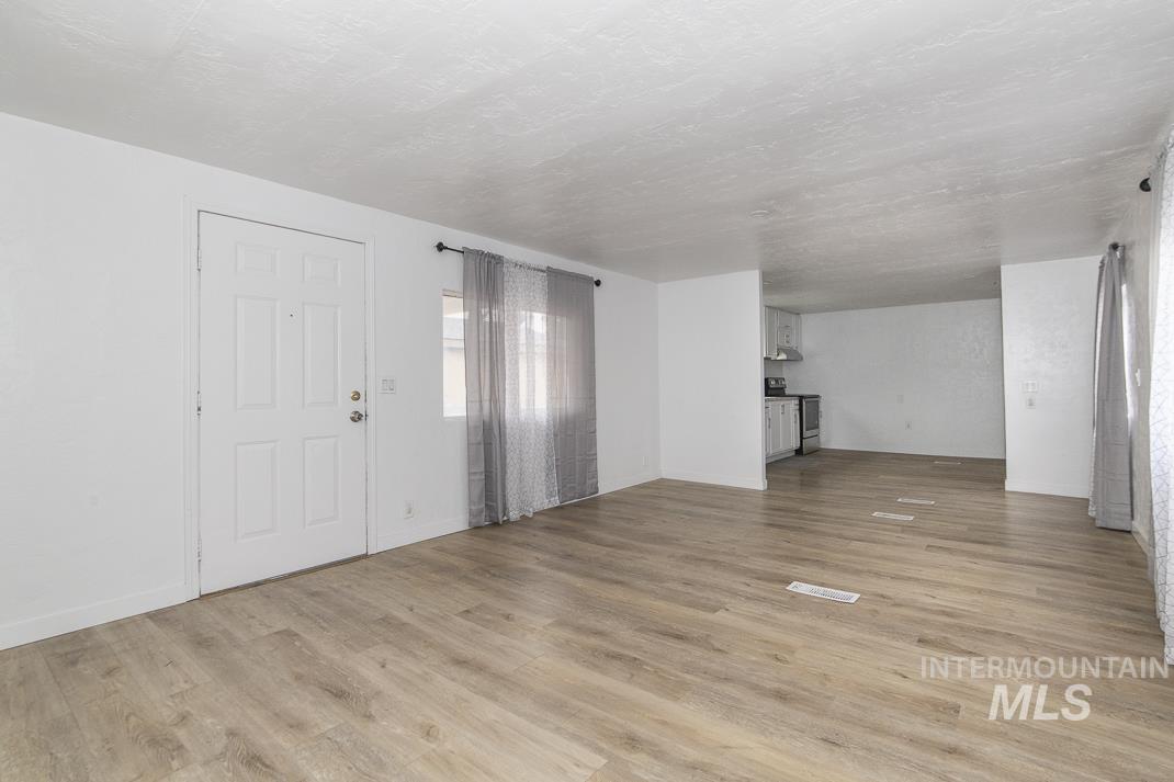 Unfurnished living room featuring light wood-style flooring and a textured ceiling