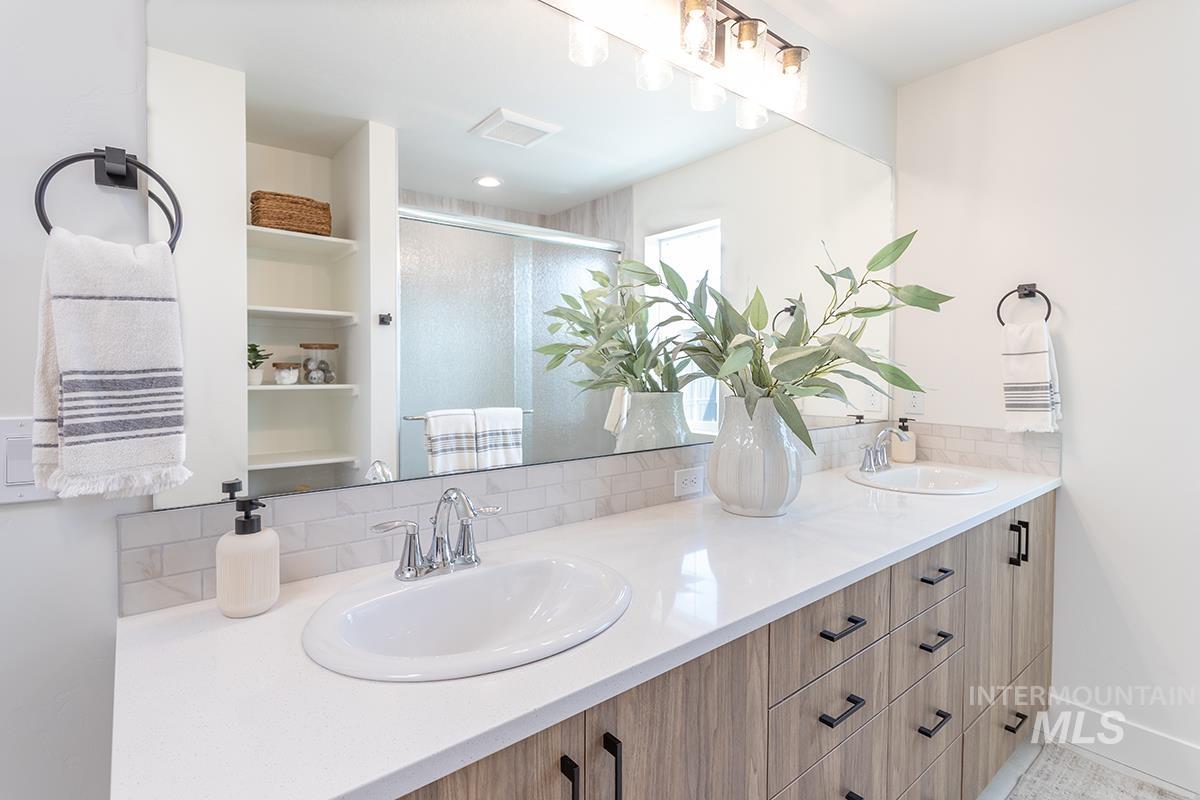Bathroom with double vanity, a shower stall, and backsplash