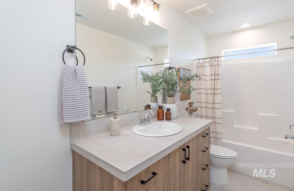 Full bathroom with vanity, shower / bath combo with shower curtain, and light tile patterned floors