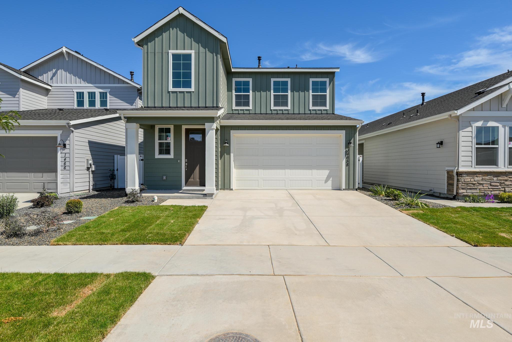 View of front facade with board and batten siding, driveway, a porch, a garage, and a front yard