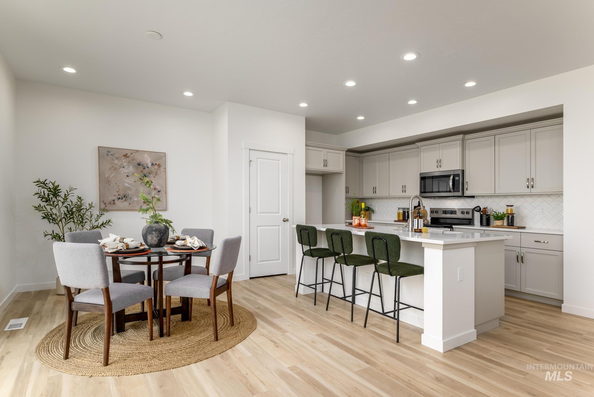 Kitchen featuring an island with sink, a breakfast bar area, appliances with stainless steel finishes, decorative backsplash, and recessed lighting