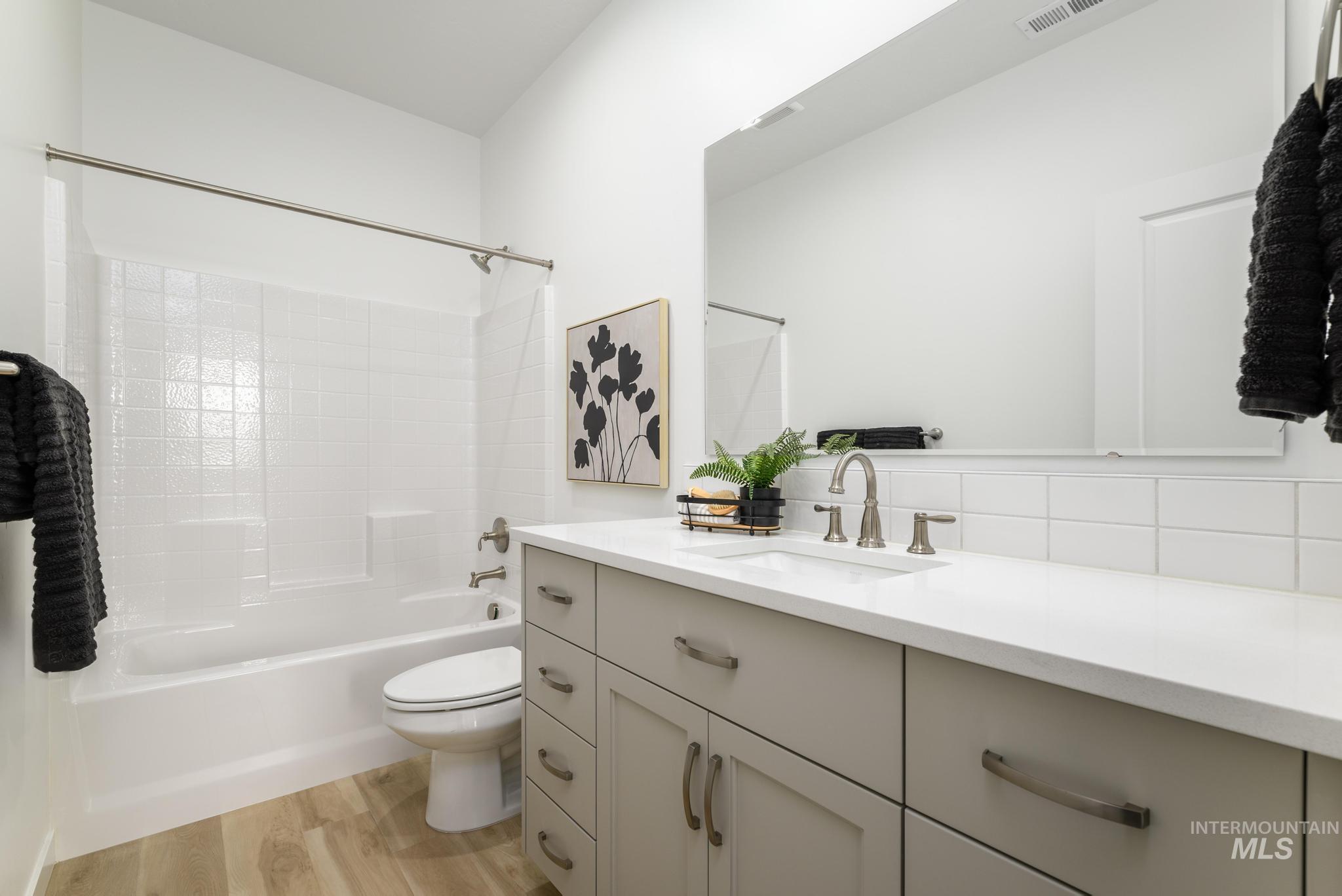 Bathroom featuring vanity,  shower combination, and light wood-type flooring