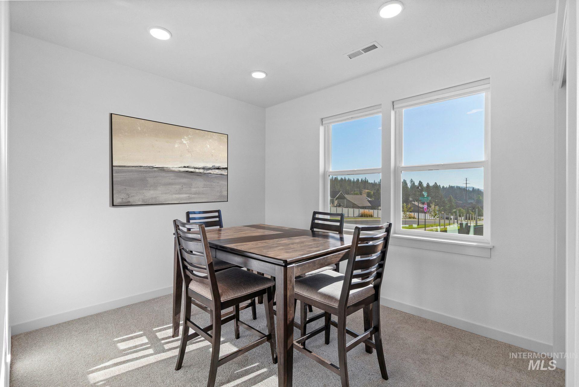 Dining area with light carpet and recessed lighting