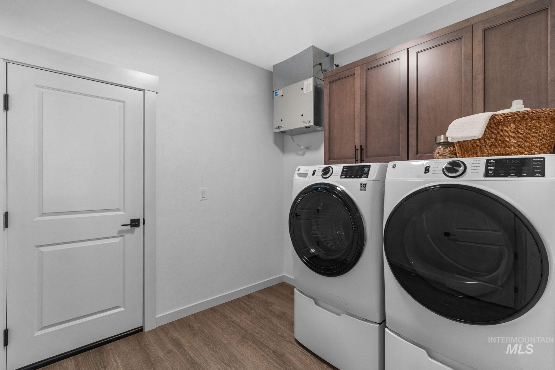 Laundry room featuring wood finished floors, washing machine and clothes dryer, and cabinet space