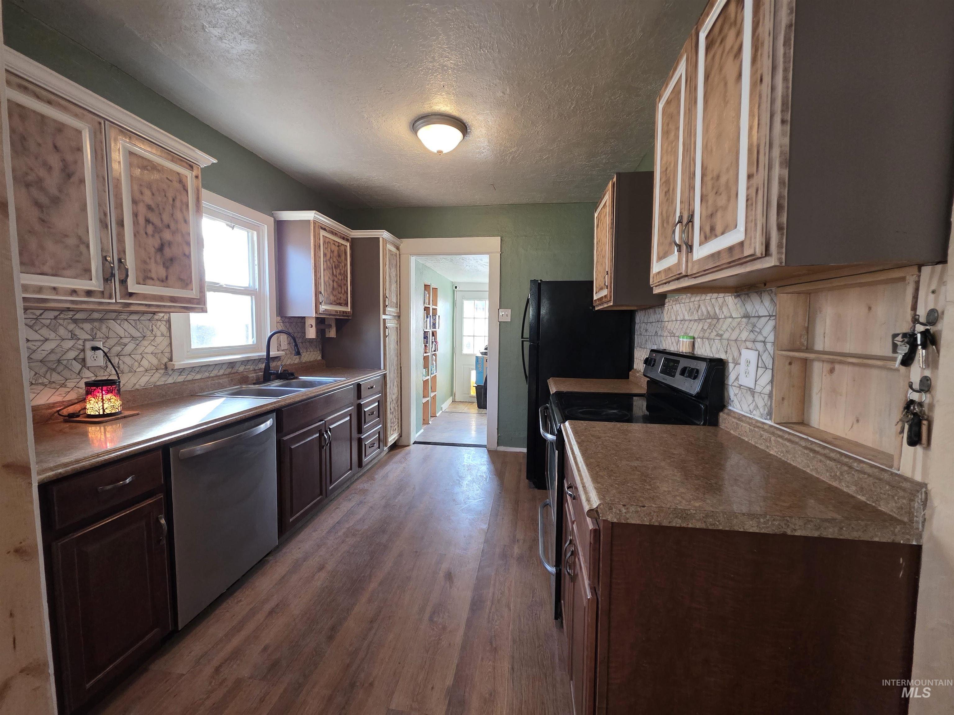 Kitchen with range with electric cooktop, stainless steel dishwasher, tasteful backsplash, a textured ceiling, and dark wood-type flooring
