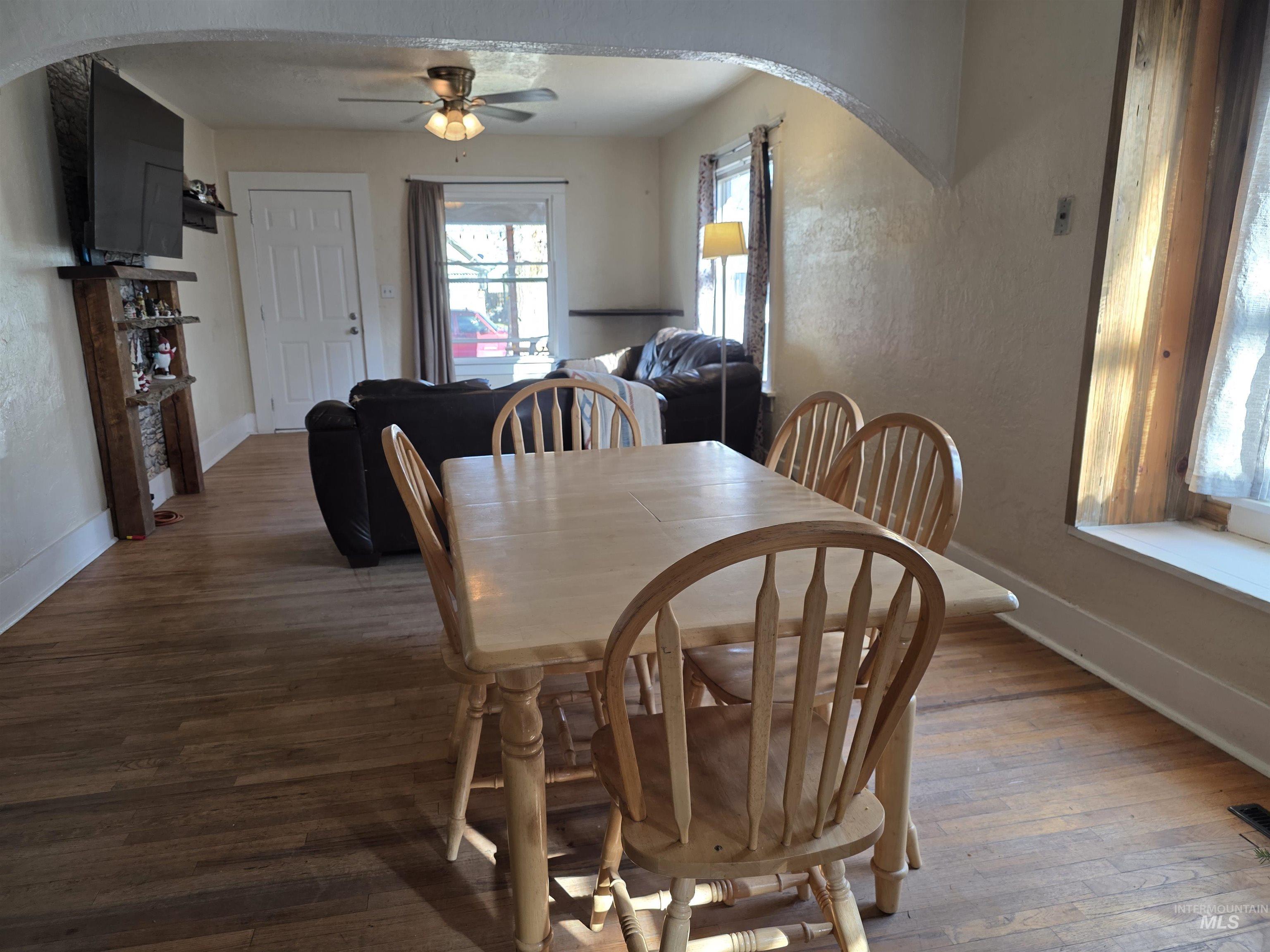 Dining space with arched walkways, hardwood / wood-style floors, and ceiling fan