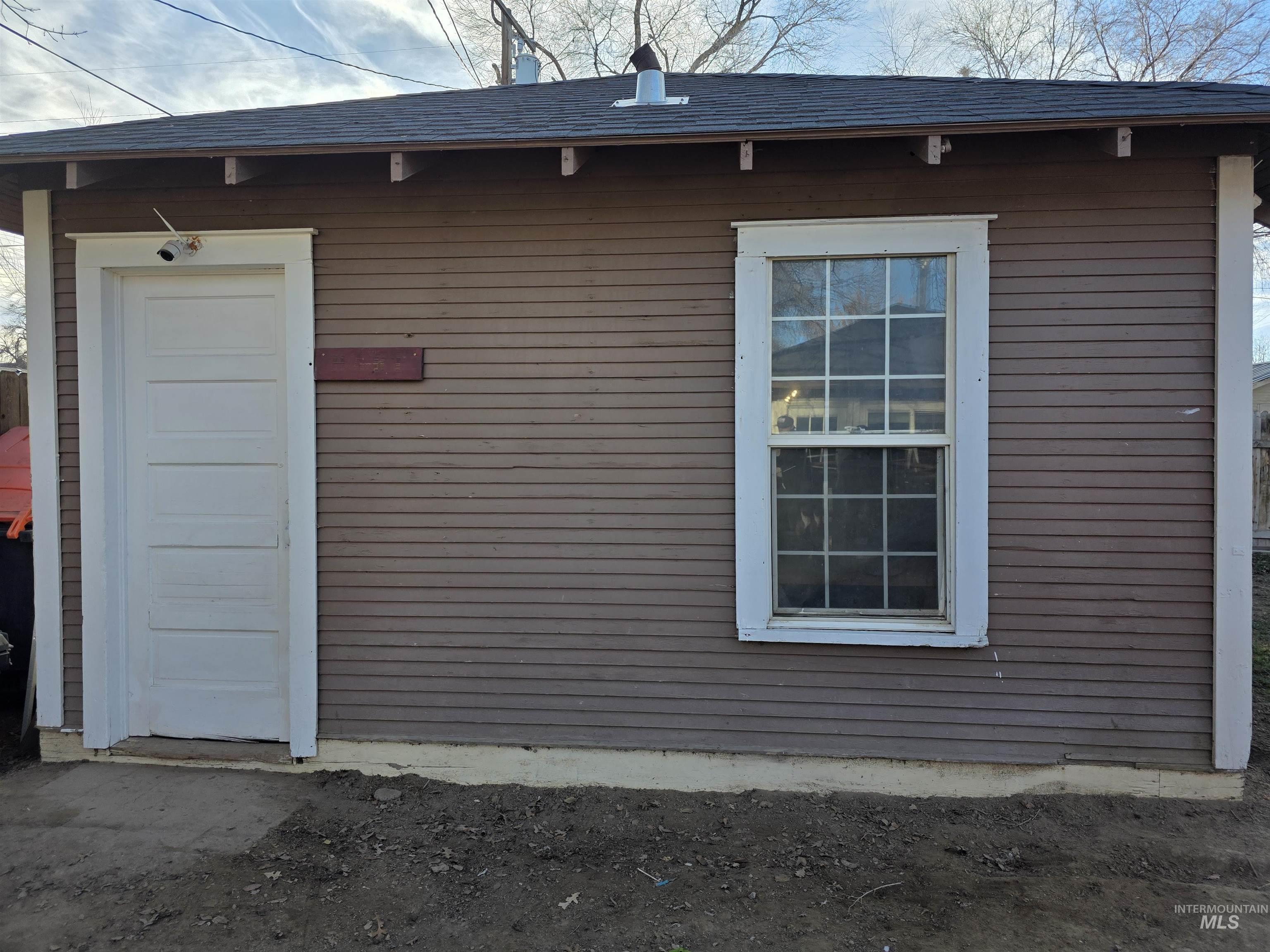 View of home's exterior with a shingled roof and an outdoor structure