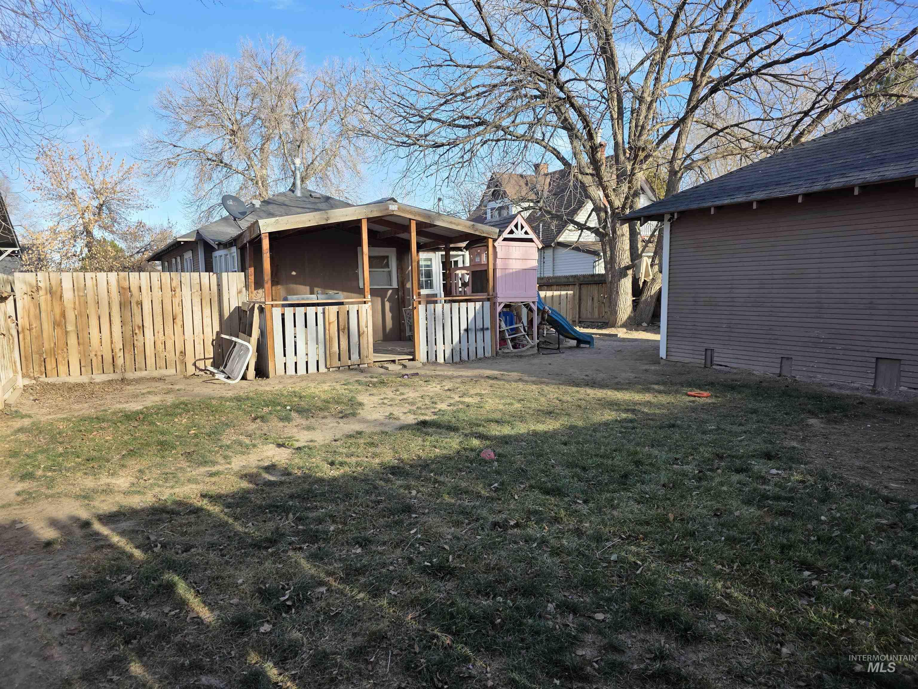 Fenced backyard featuring a playground
