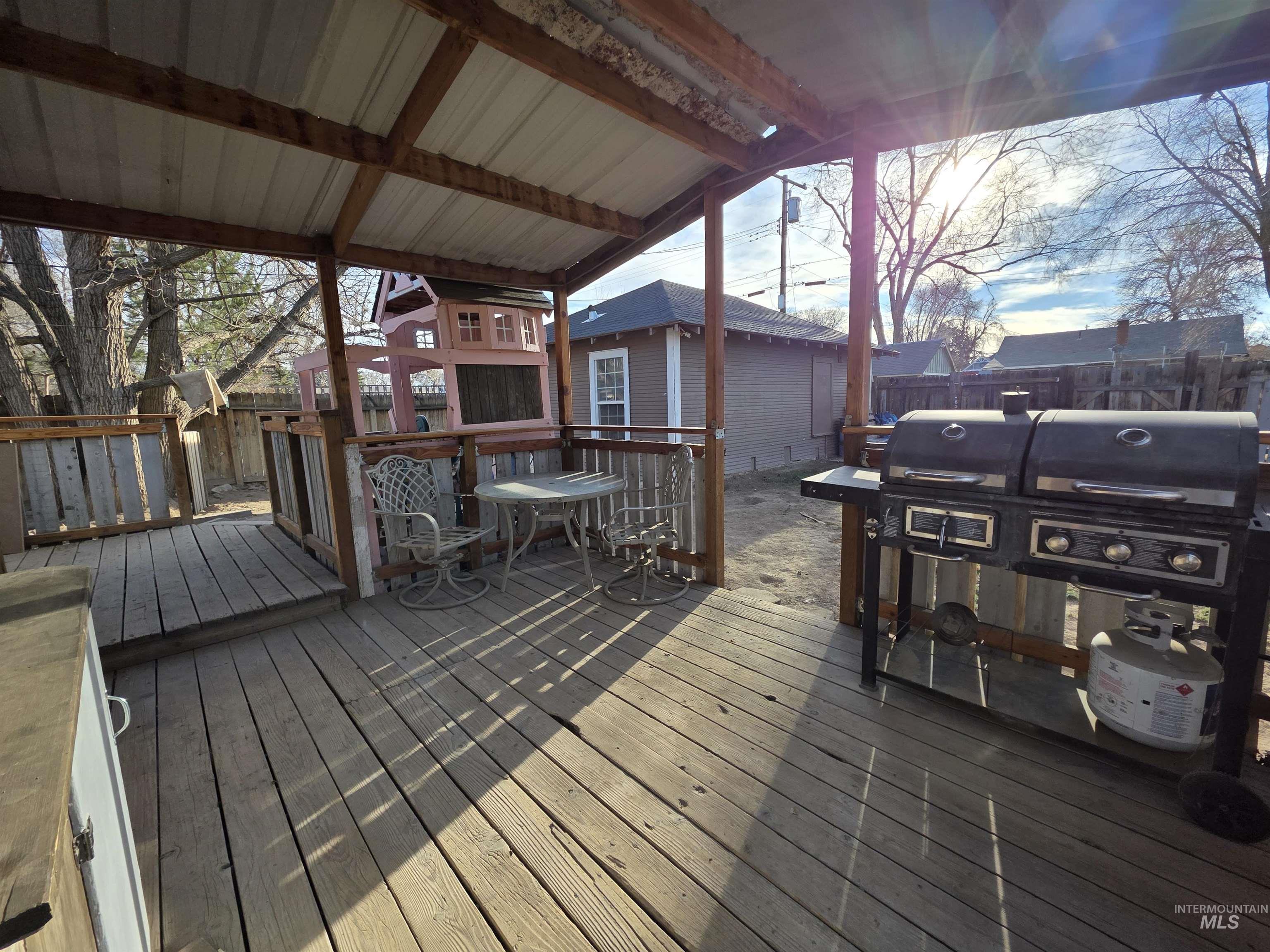 Wooden terrace with a fenced backyard