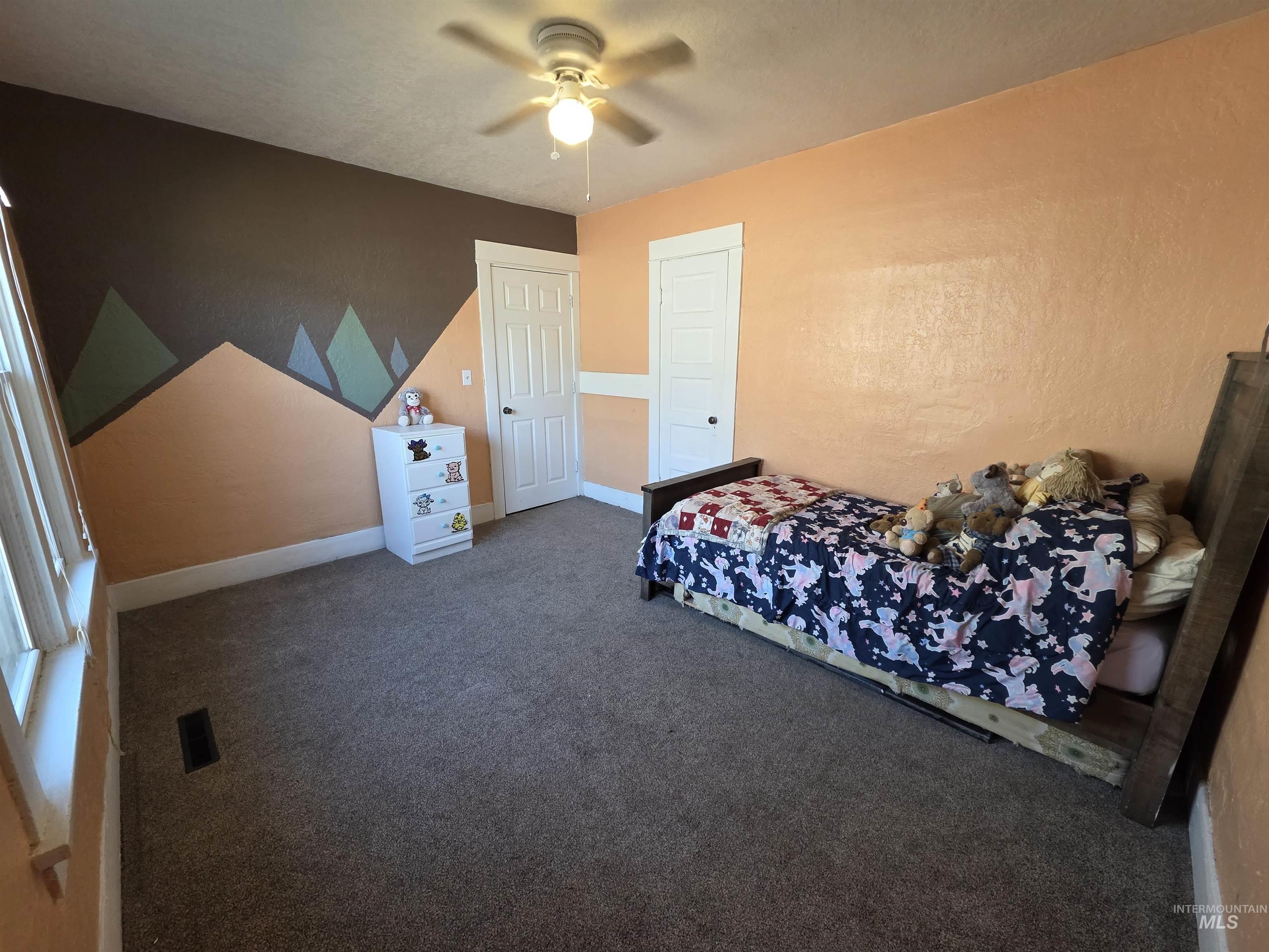 Bedroom featuring carpet floors, a ceiling fan, and a textured wall