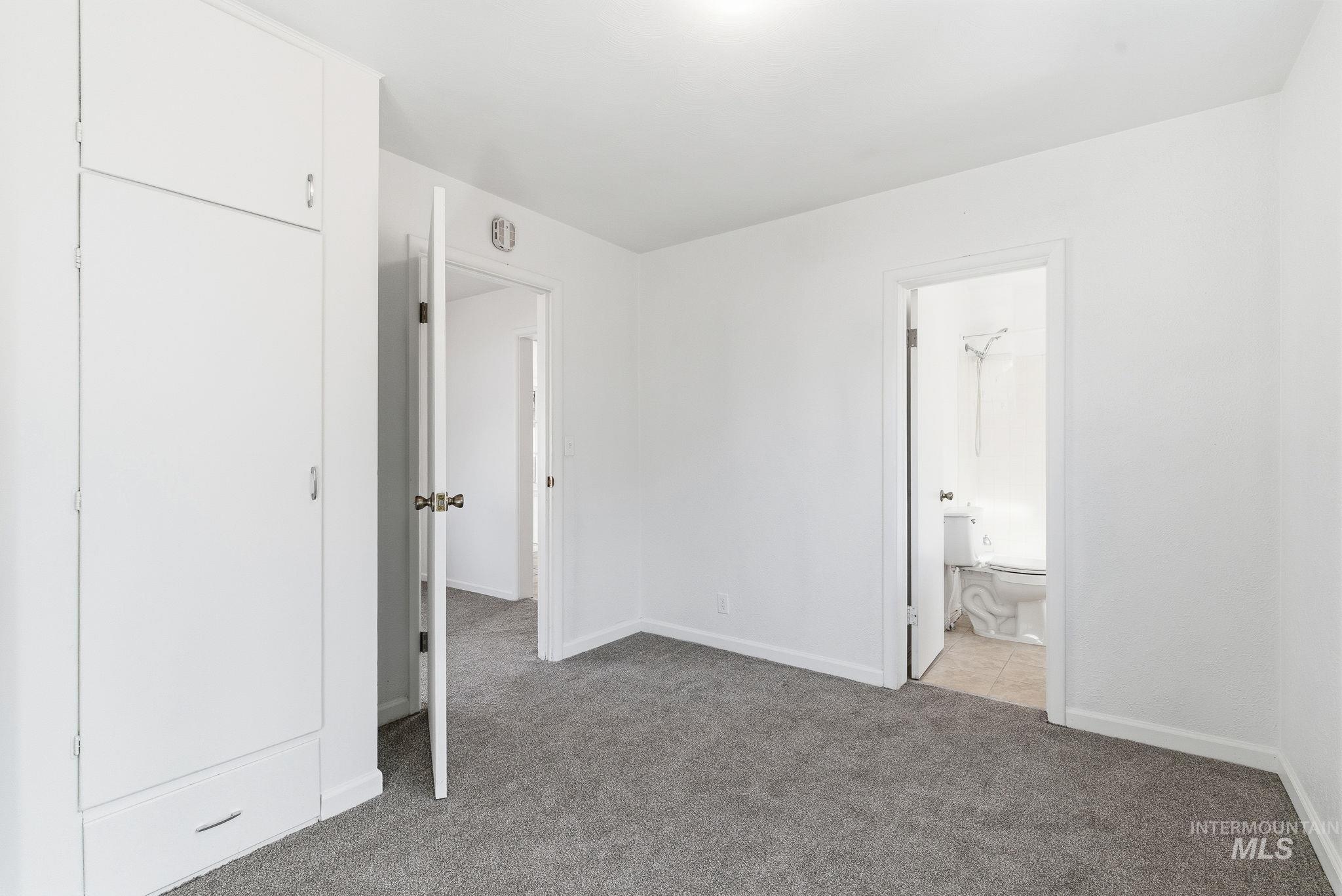 Unfurnished bedroom featuring light colored carpet and ensuite bathroom