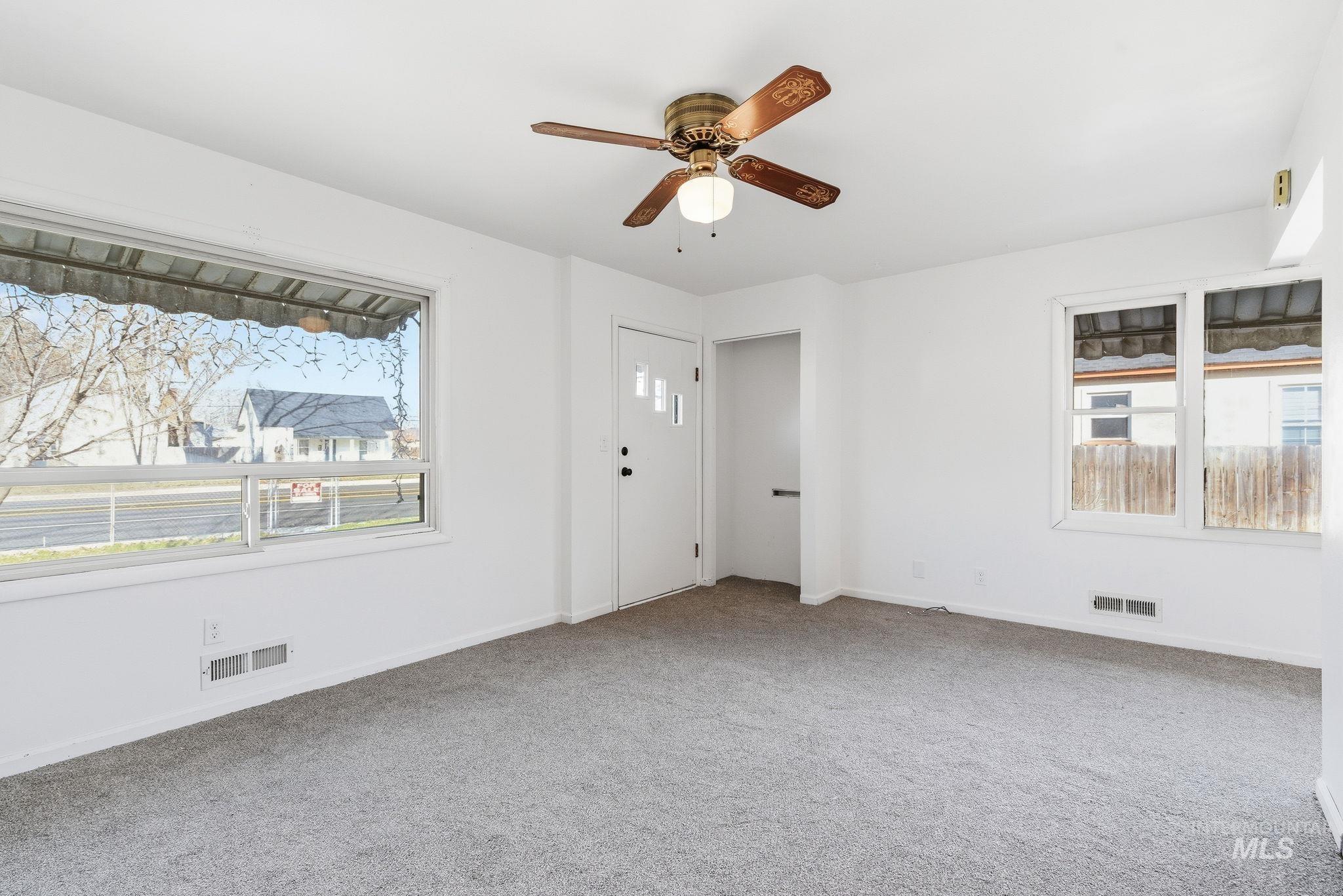 Spare room featuring light carpet, healthy amount of natural light, and a ceiling fan
