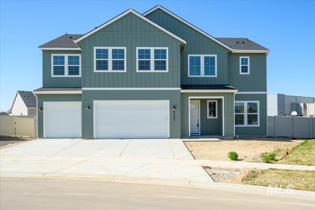 View of front of house with driveway, an attached garage, board and batten siding, and a gate