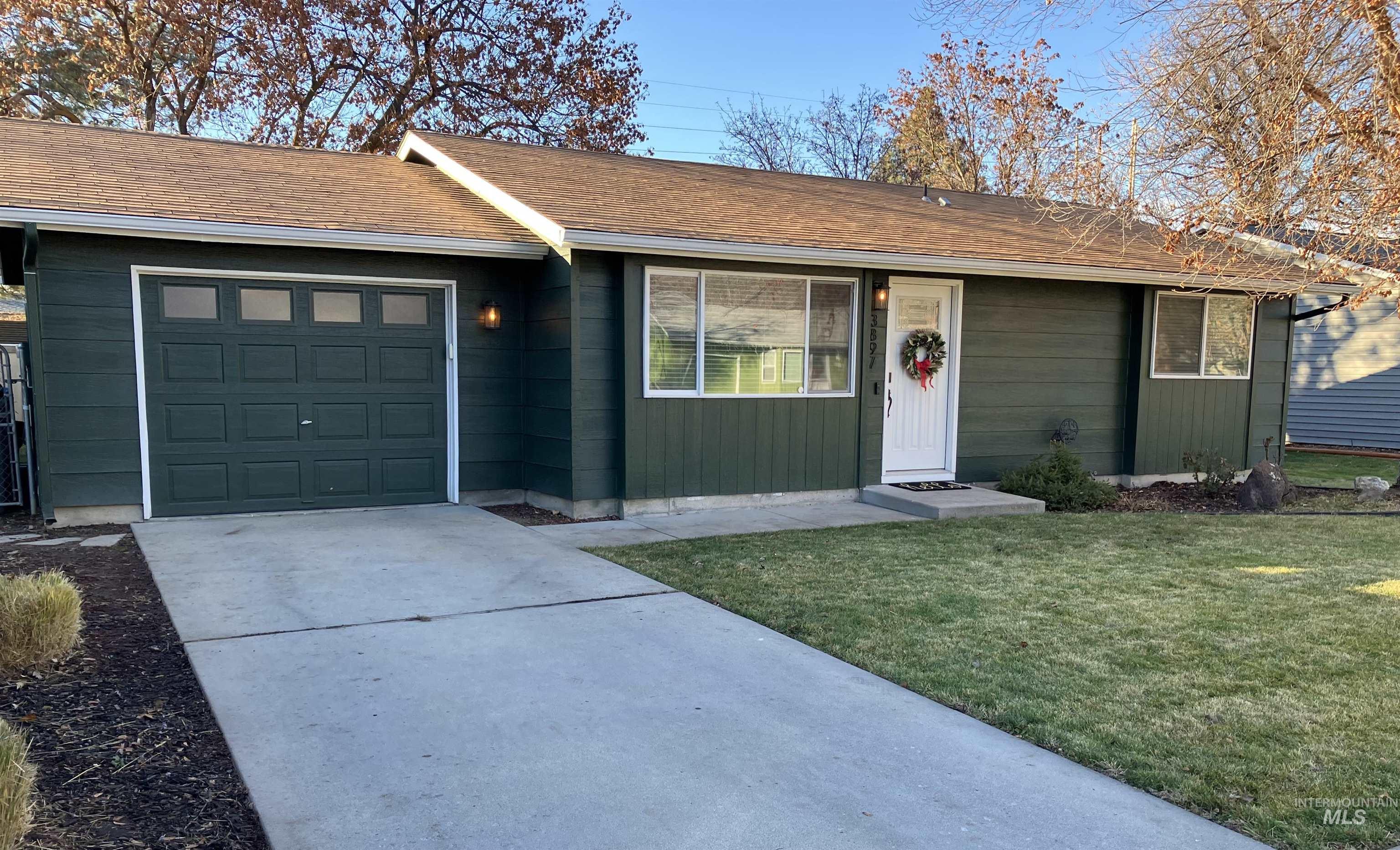 Single story home with concrete driveway, a front yard, and a garage