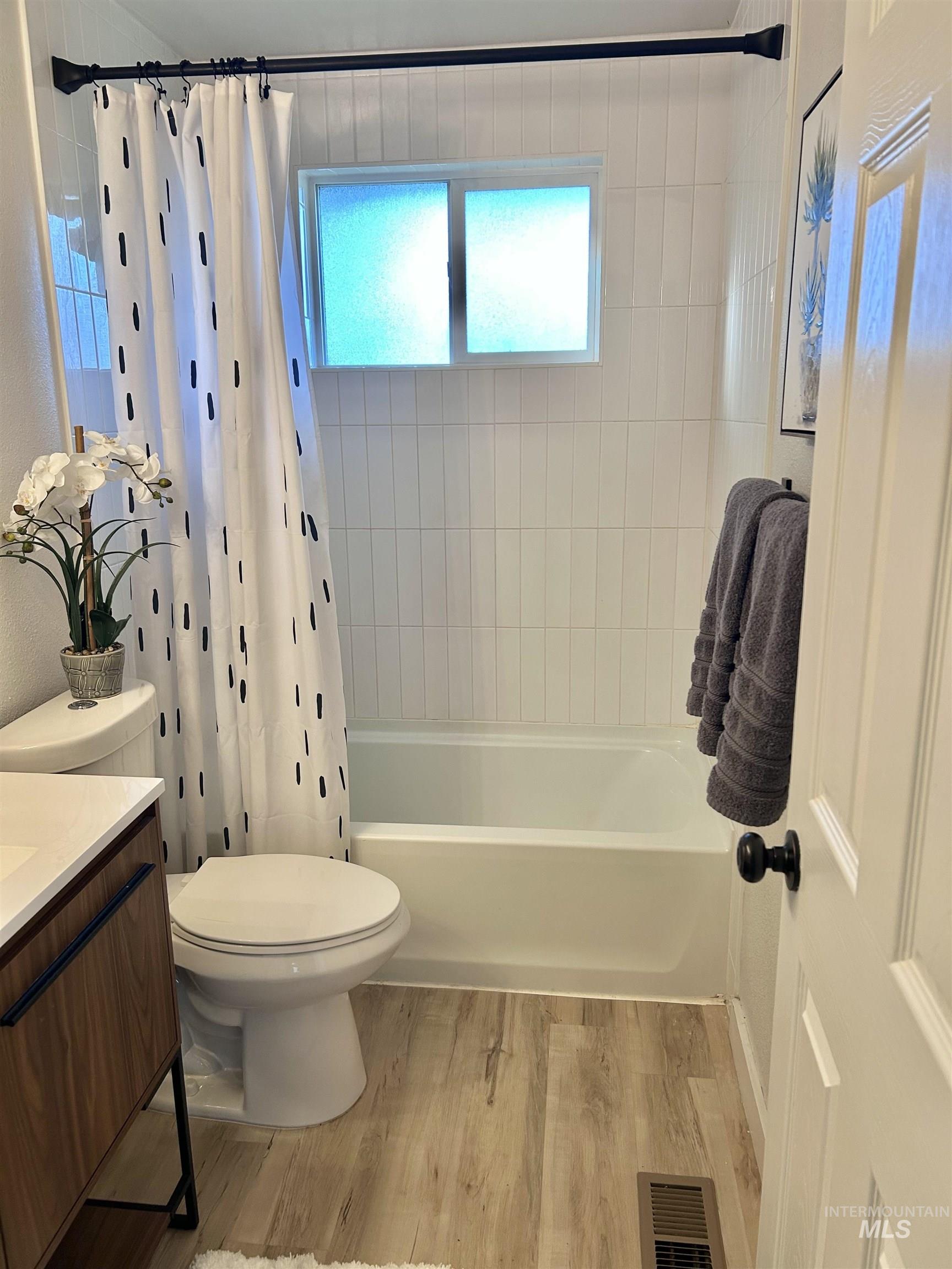 Full bathroom featuring vanity, light wood-style floors, and shower / bath combo with shower curtain